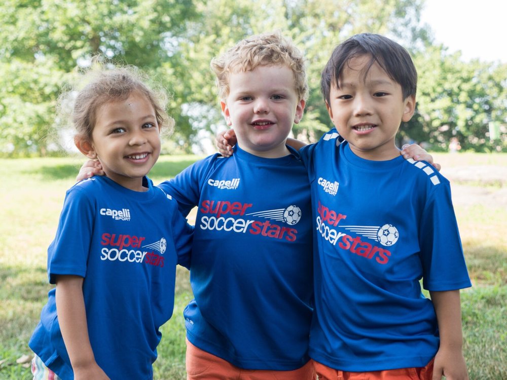 Three smiling kids in Super Soccer Stars jerseys