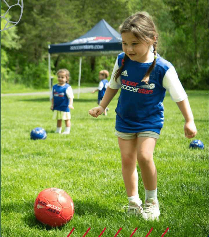 A girl dribbles a ball on the grass